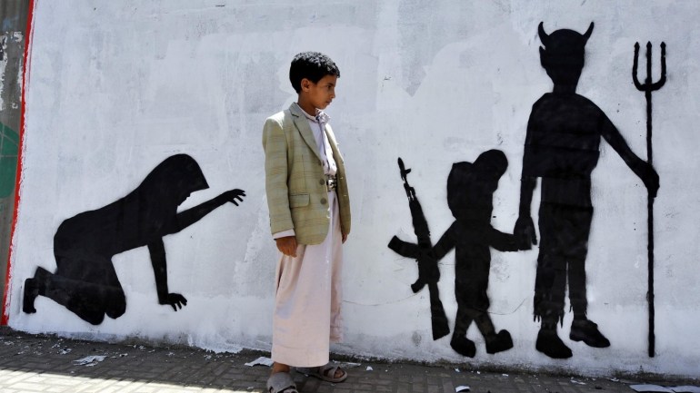 A Yemeni boy looks at graffiti sprayed on a wall depicting a child soldier walking with evil during a campaign to end the recruitment and use of children in conflicts, in Sanaa, Yemen, 10 April 2014. Yemeni artists launched a campaign to end the recruitment of child soldiers by tribal militias and rebel groups in the country's violent conflicts.