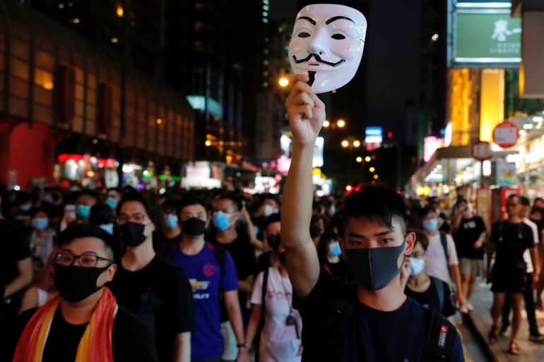 Anti-extradition bill protester raises a Guy Fawkes mask as he marches at Hong Kong's tourism district Nathan Road near Mongkok, China July 7, 2019. REUTERS/Tyrone Siu