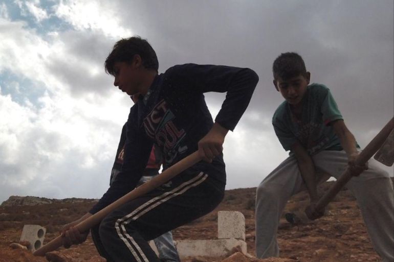 الطفل أحمد يحفر القبر ويجهزه لاستقبال جثمان أحد السوريين في ريف إدلب