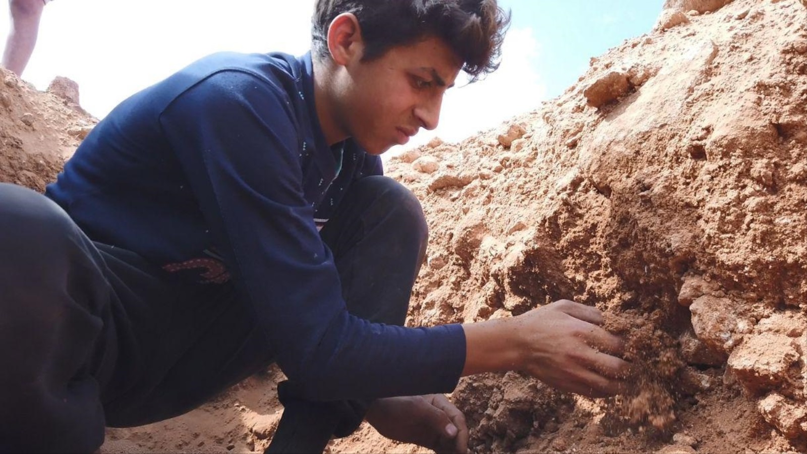 أحمد يحفر القبر بعمق متر أو أكثر وفقا لرغبة أهالي المتوفى(الجزيرة)