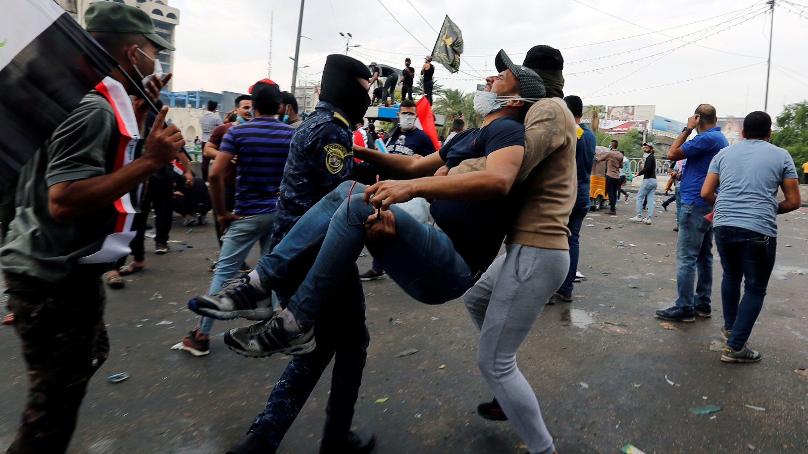 متظاهرون في بغداد يحملون زميلا لهم أصيب خلال مواجهات مع قوات الأمن (رويترز)