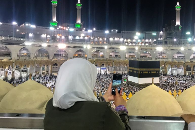 Muslim Hajj pilgrims at Masjid al-Haram in Mecca- - MECCA, SAUDI ARABIA - AUGUST 10: A woman takes a photo as Muslim Hajj pilgrims perform morning prayer around the Kaaba, Islam's holiest site, located in the center of the Masjid al-Haram (Grand Mosque) in Mecca, Saudi Arabia on August 10, 2018.