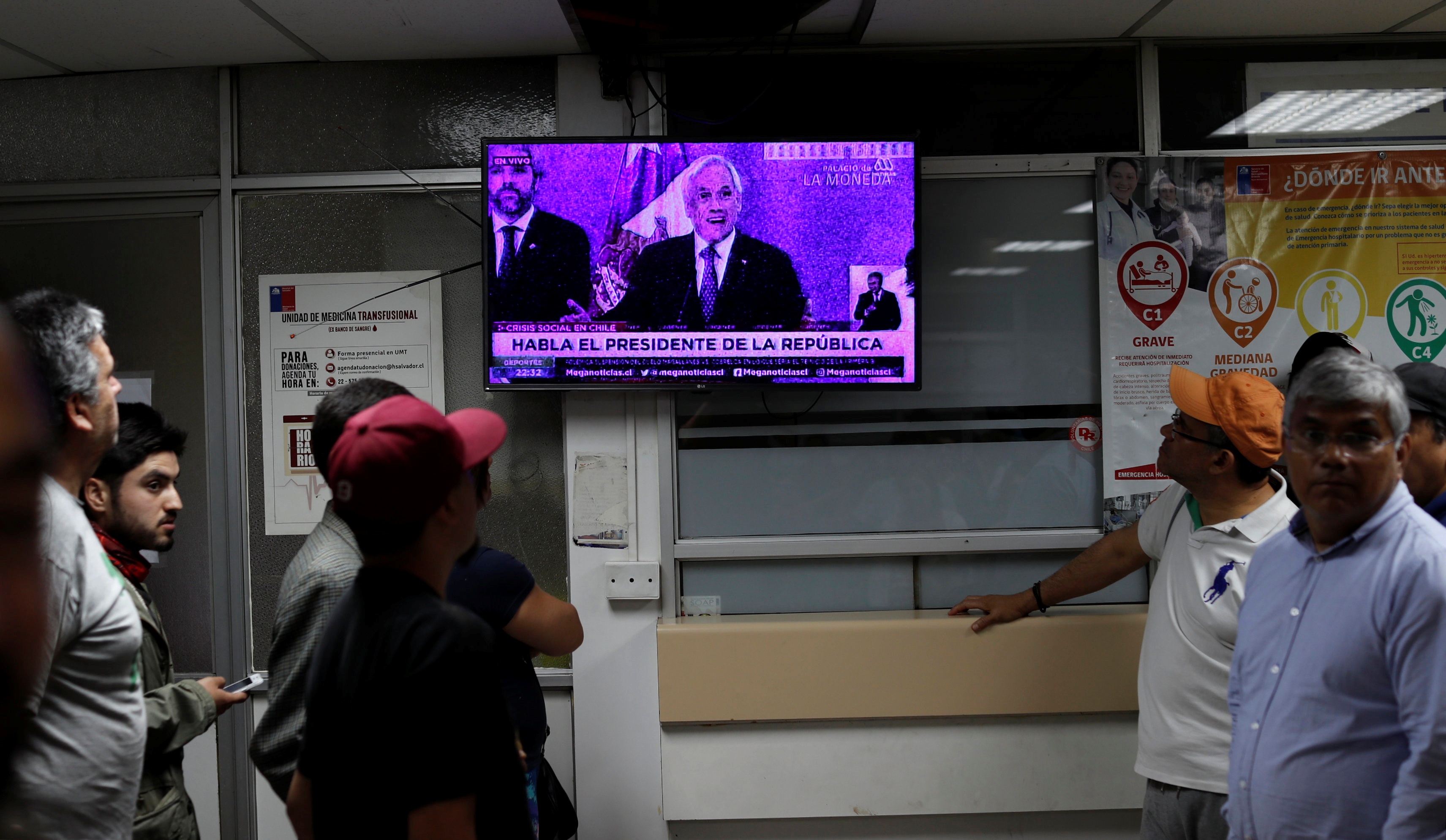 مواطنون يشاهدون خطاب الرئيس التشيلي سباستيان بينييرا بعد الاحتجاجات هناك (رويترز)
