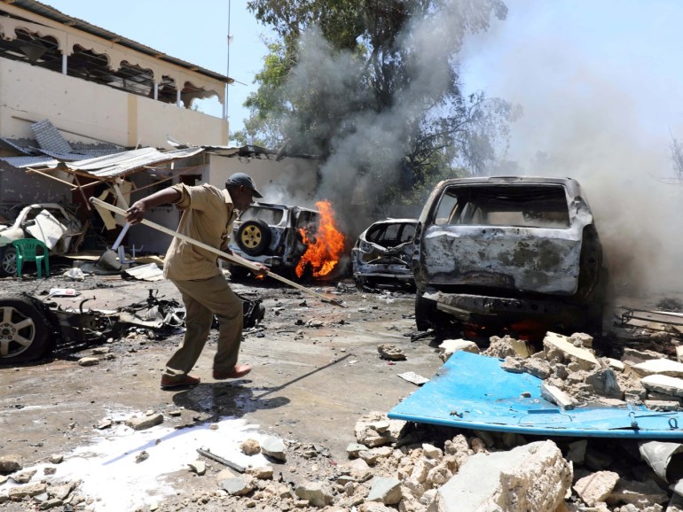 A Somali man uses a pole to search under a car at the scene where a car bomb exploded in front of a restaurant in Mogadishu, Somalia January 29, 2019. REUTERS/Feisal Omar