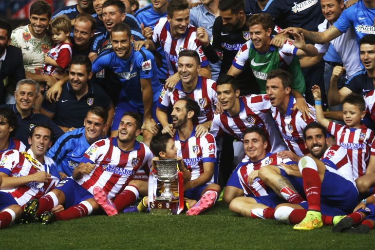 Atletico Madrid's team members celebrate with the trophy after they won the Spanish Super Cup against Real Madrid at the Vicente Calderon stadium in Madrid August 23, 2014. REUTERS/Juan Medina (SPAIN - Tags: SPORT SOCCER)ATTENTION EDITORS - SPANISH LAW REQUIRES THAT THE FACES OF MINORS ARE MASKED IN PUBLICATIONS WITHIN SPAIN