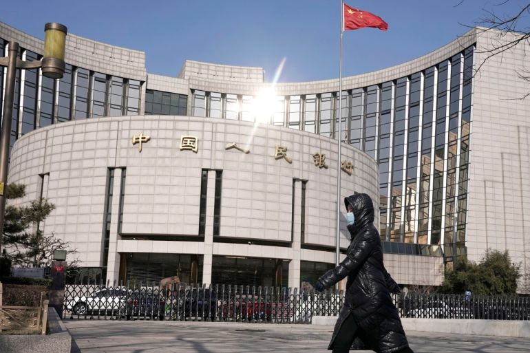 A woman wearing a mask walks past the headquarters of the People's Bank of China, the central bank, in Beijing, China, as the country is hit by an outbreak of the new coronavirus, February 3, 2020. REUTERS/Jason Lee