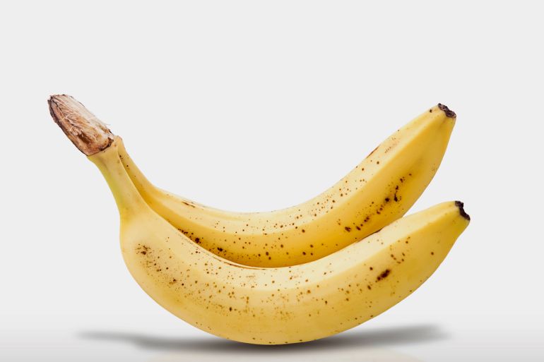 No People; Tropical Fruit; Two Objects; Copy Space; Banana; White Background; Fruit; Freshness; Food; Close-Up; Food And Drink; Still Life; Studio Shot; Cut Out; Shadow; Yellow; Horizontal Image