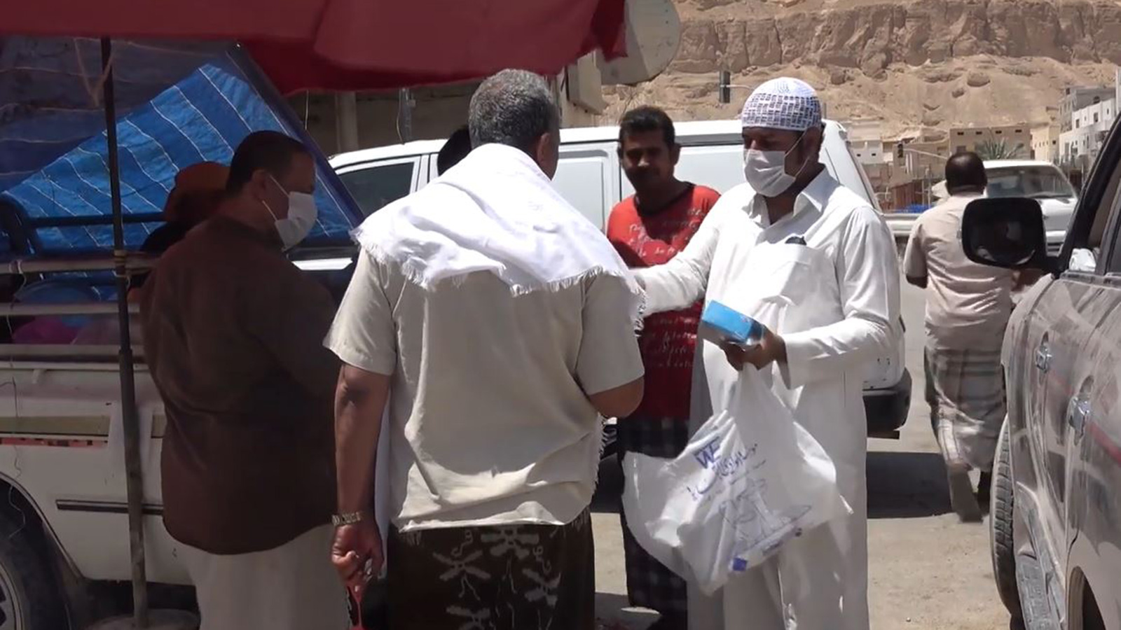‪أحد شباب حملات التوعية بفيروس كورونا يوزع الكمامات على الناس في حضرموت‬ (الجزيرة)