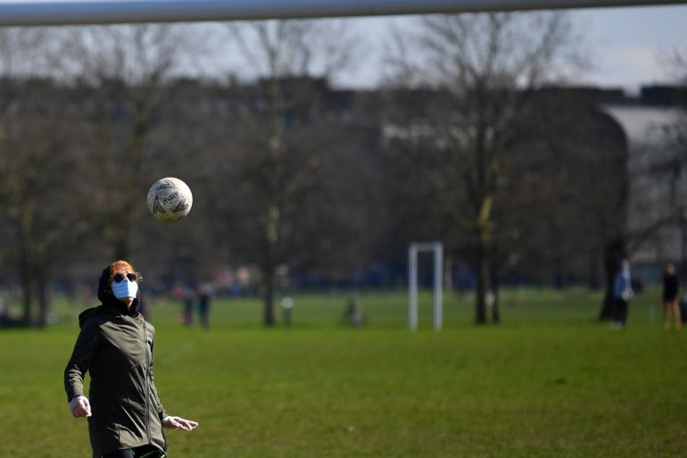 A woman wearing a mask plays football on Clapham Common, as the number of coronavirus disease (COVID-19) cases grow around the world, in London, Britain March 22, 2020. REUTERS/Dylan Martinez