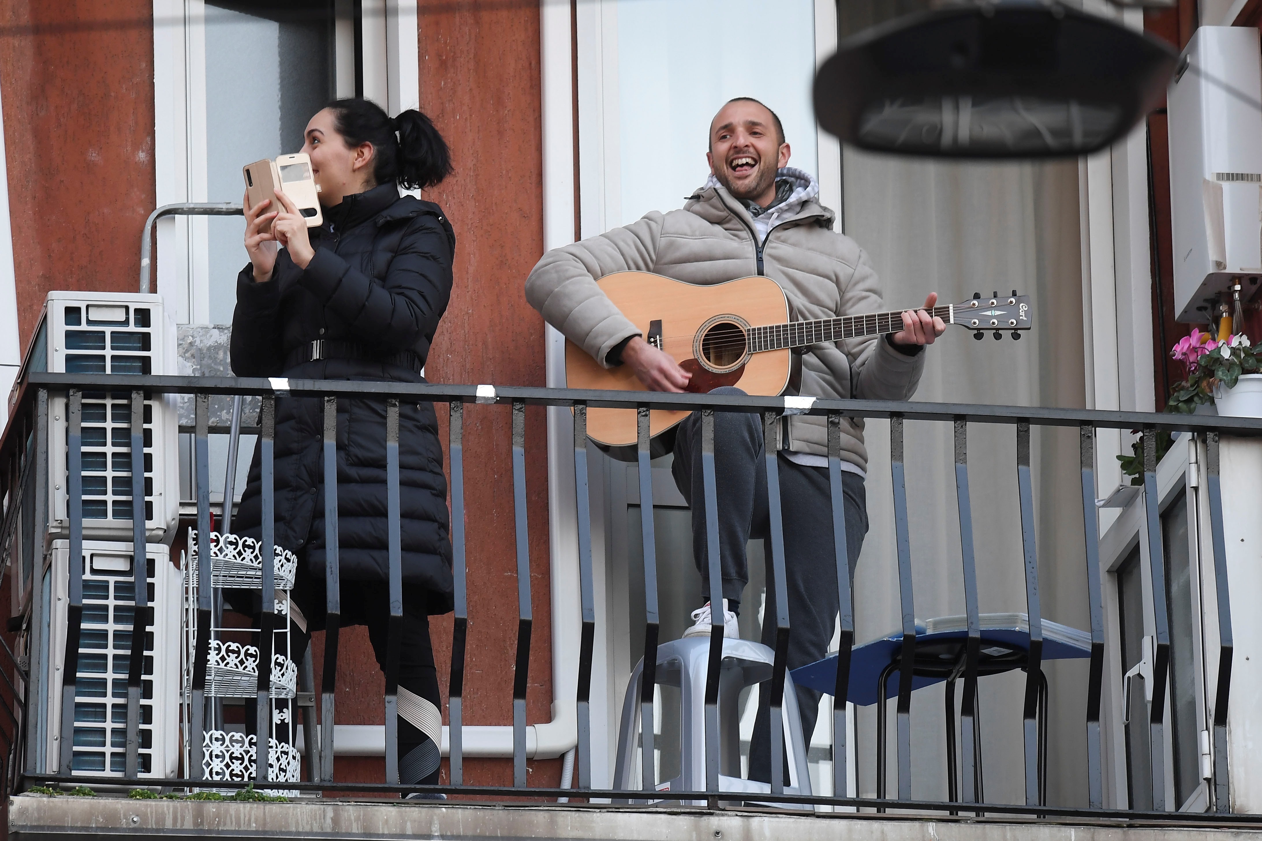 رجل إيطالي يعزف في الشرفة بعد إجراءات الحكومة الإيطالية للحد من انتشار فيروس كورونا (رويترز)