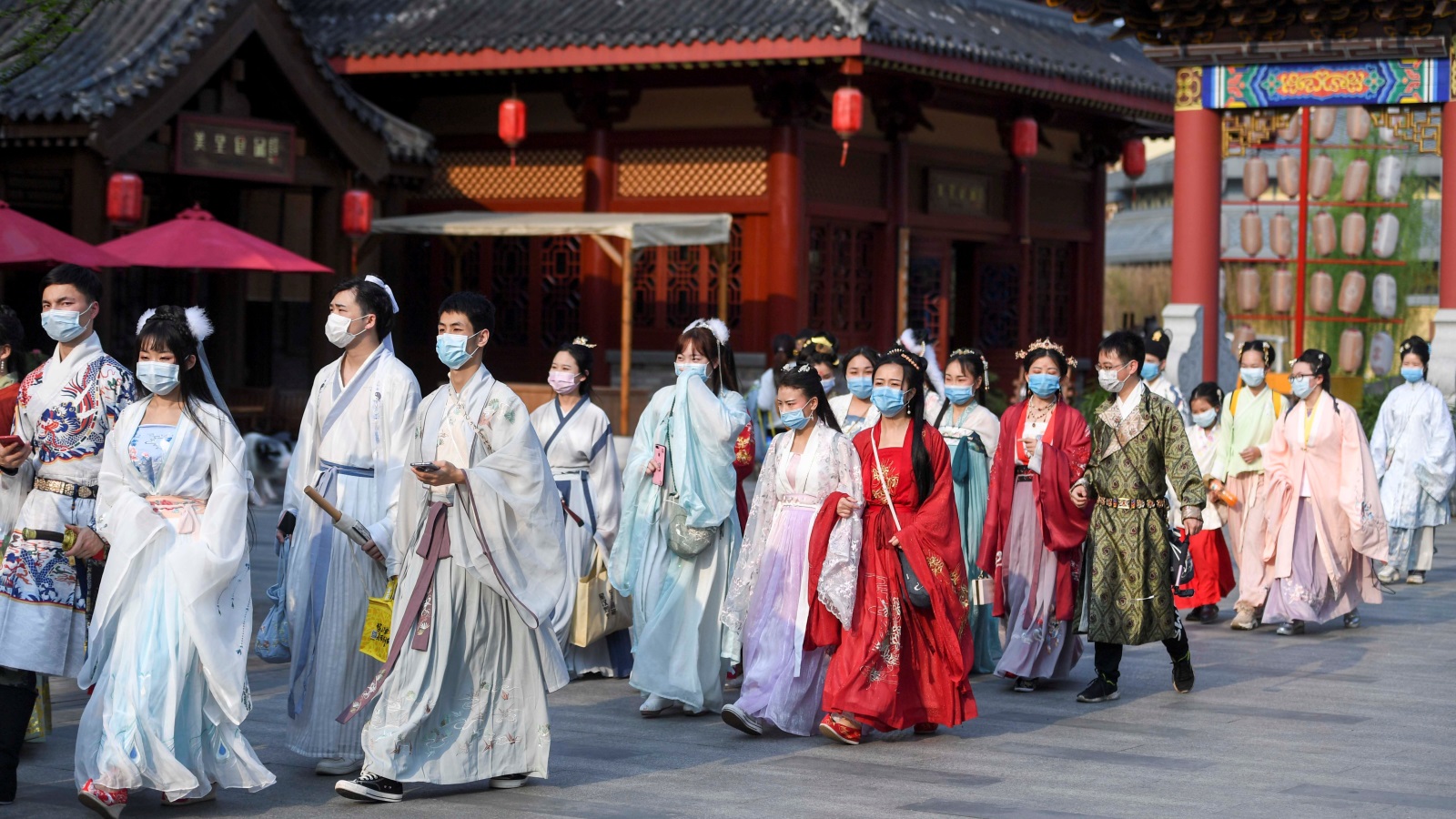 ‪صينيون يرتدون أزياء تقليدية وأقنعة واقية من انتشار وباء كورونا يتجولون بأحد منتزهات العاصمة بكين‬ (رويترز)