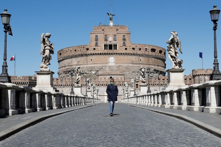 A woman wearing a protective mask walks outside Castel Sant'Angelo, as Italy tightens measures to try and contain the spread of coronavirus disease (COVID-19), in Rome, Italy March 23, 2020. REUTERS/Remo Casilli TPX IMAGES OF THE DAY