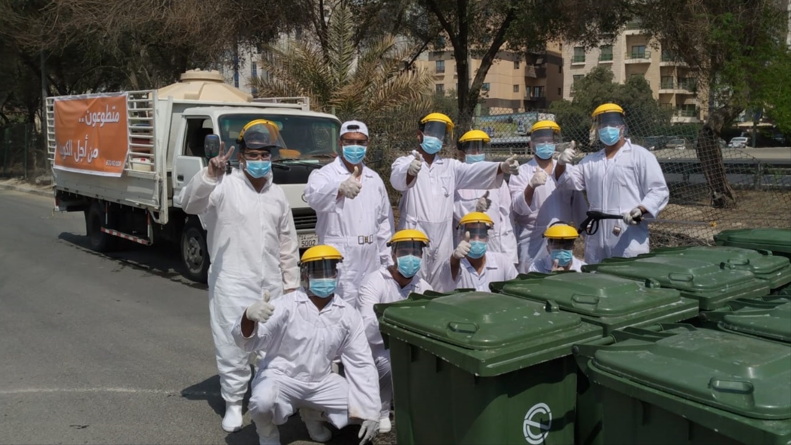 ‪متطوعون في حملة تعقيم حاويات القمامة بالكويت‬ (الجزيرة)