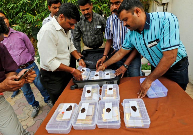 Indian police officials pack seized gold bars in a bag after they displayed it at a police station in Ahmedabad (رويترز)