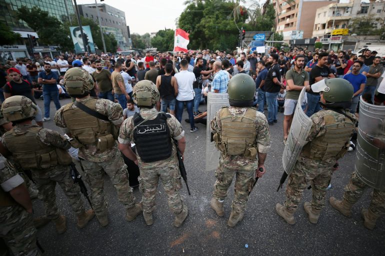 Lebanese army soldiers stand guard as demonstrators take part in a protest targeting the government over an economic crisis in the port city of Sidon