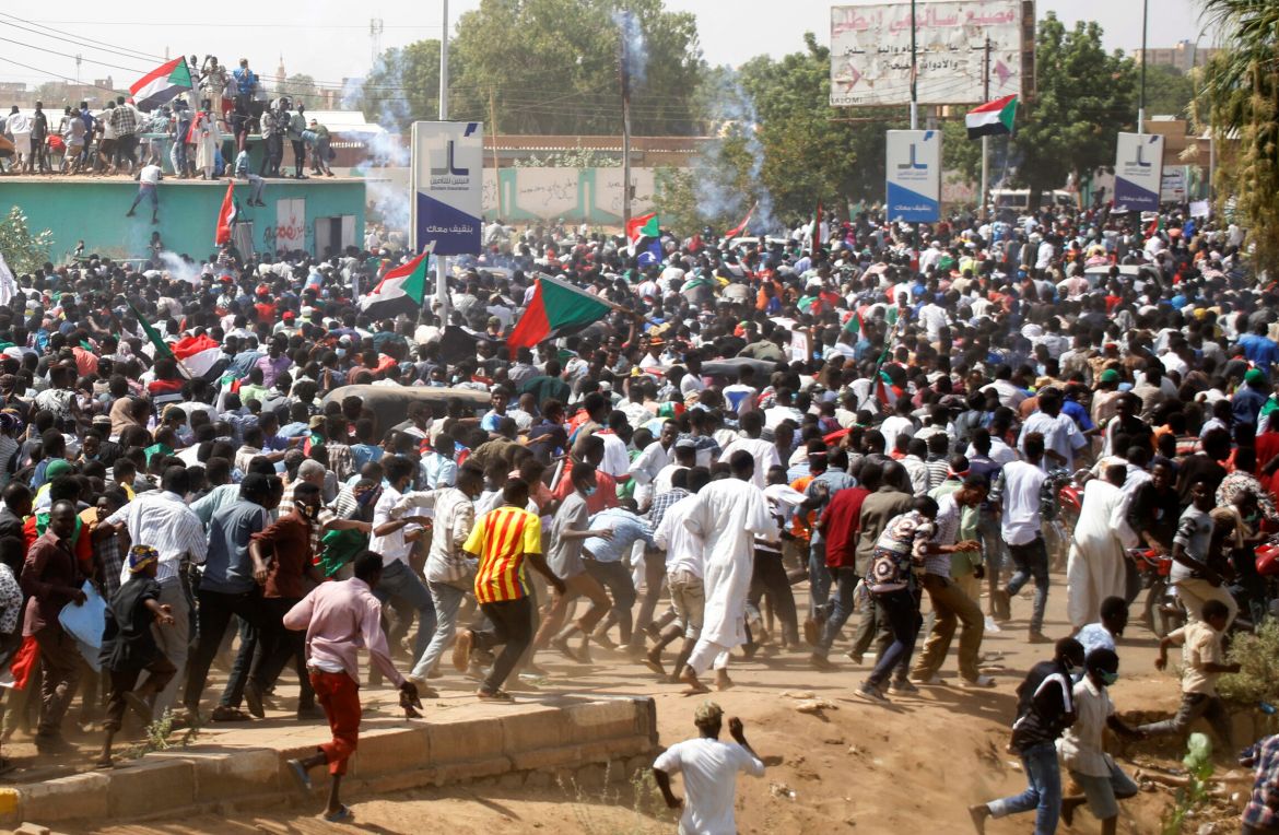 Protesters run after they were dispersed by riot-police officers near the Parliament buildings, in in Omdurman, Khartoum
