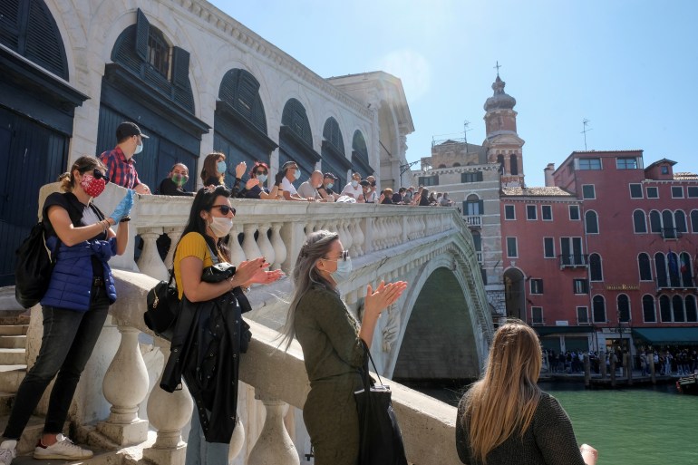 A rally organised by small business owners stops by the Rialto bridge to commemorate the health care workers as Italy begins a staged end to a nationwide lockdown due to a spread of the coronavirus disease (COVID-19), in Venice