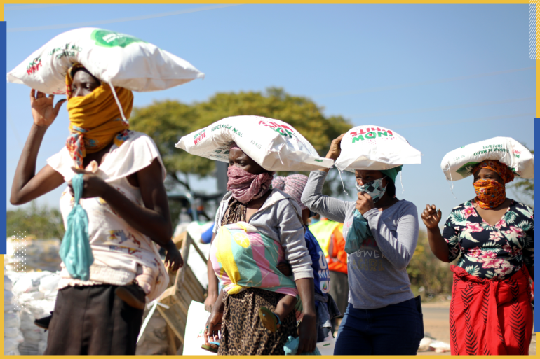 Women carry bags of maize meal on their heads as people queue to receive food aid amid the spread of the coronavirus disease (COVID-19) outbreak, at the Itireleng informal settlement, near Laudium suburb in Pretoria, South Africa, May 20, 2020. REUTERS/Siphiwe Sibeko