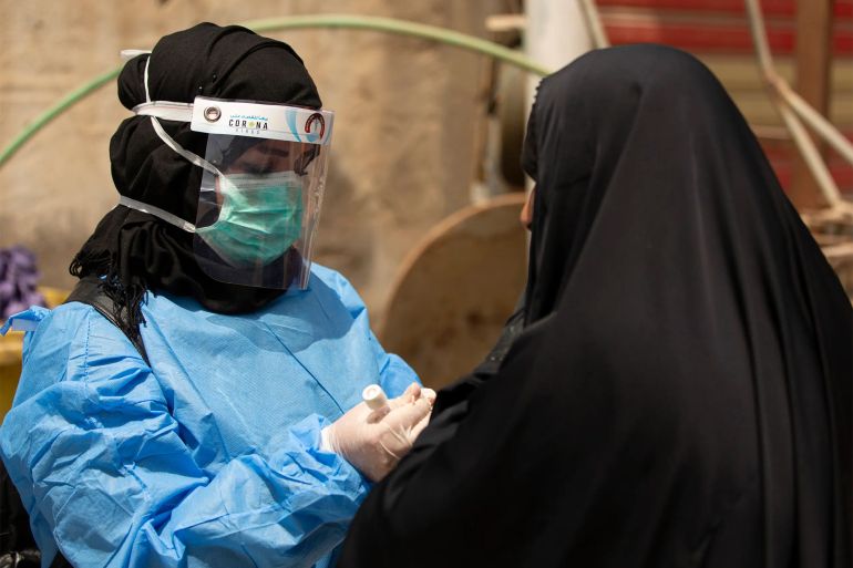 (FILES) In this file photo taken on June 02, 2020 a medical worker prepares to take a swab from a woman being tested for COVID-19 coronavirus disease, in the 5-Miles district of Iraq's southern Basra on June 2, 2020. - Iraq has registered more than 45,000 coronavirus cases, with doctors increasingly infected. In the semi-autonomous Kurdish north, a recent surge in coronavirus infections has pushed infected cases there over 5,000 -- including at least 200 health workers -- and the deaths to more than 160. (Photo by Hussein FALEH / AFP)