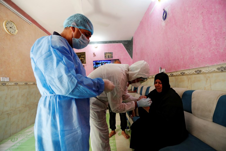 A healthcare worker takes blood samples from a woman during testing for the coronavirus disease (COVID-19) in Sadr city, district of Baghdad