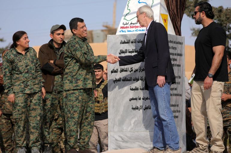 Mazloum Kobani, SDF's commander in chief, shakes hands with advisor for the US Department of State in northern Syria William Robak, at al-Omar oil field in Deir Al Zor