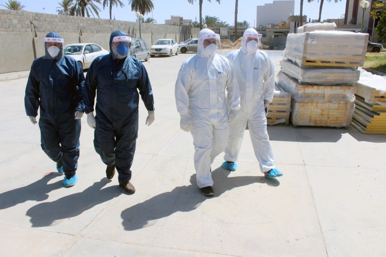 Medical team wearing protective suits walk to a clinic, following the outbreak of the coronavirus disease (COVID-19), in Misrata