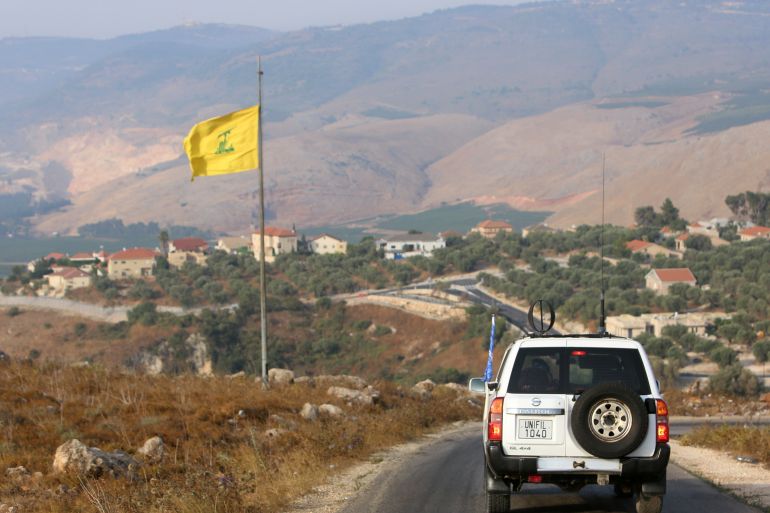 UN peacekeepers vehicle drives past a Hezbollah flag in the southern Lebanese village of Khiam