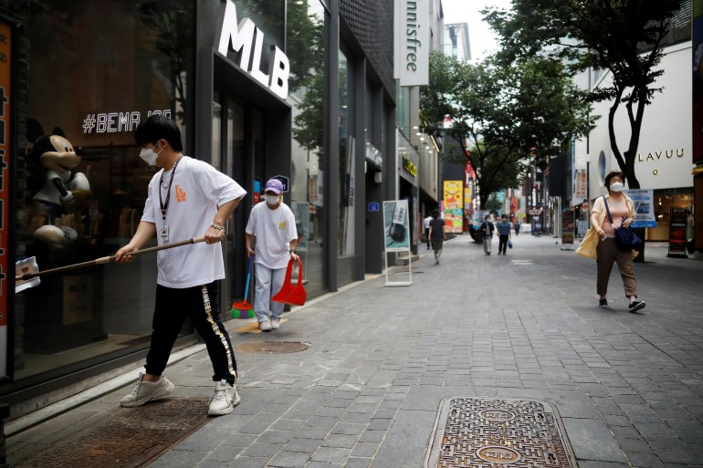 A shop assistant cleans a window as they wait for a customer at Myeongdong shopping district which is nearly empty amid the coronavirus disease (COVID-19) pandemic in Seoul