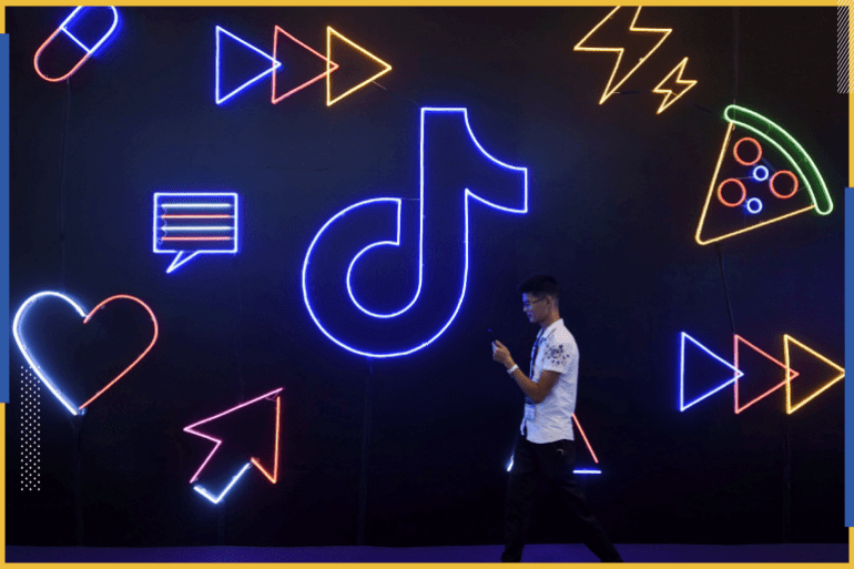 A man holding a phone walks past a sign of Chinese company ByteDance's app TikTok, known locally as Douyin, at the International Artificial Products Expo in Hangzhou, Zhejiang province, China October 18, 2019. Picture taken October 18, 2019. REUTERS/Stringer ATTENTION EDITORS - THIS IMAGE WAS PROVIDED BY A THIRD PARTY. CHINA OUT.