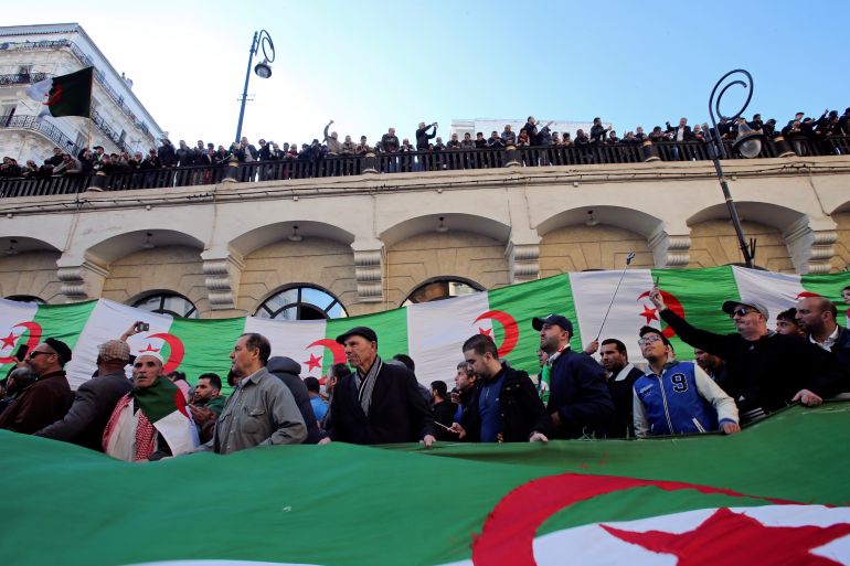 Demonstrators carry a national flag during an anti-government rally in Algiers