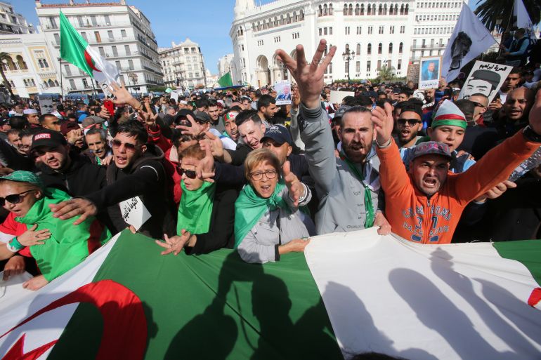 Demonstrators carry flags and gesture during an anti-government protest in Algiers
