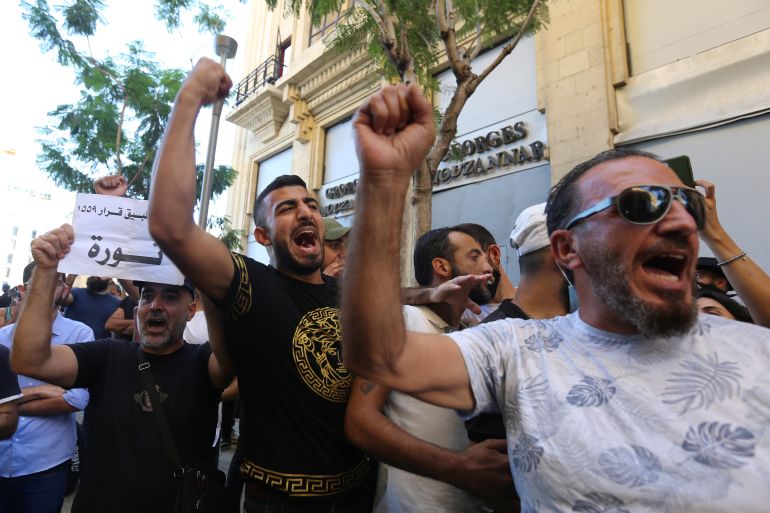 Anti-government demonstrators chant slogans and gesture during a protest as Lebanese mark one year since the start of nation-wide protests in Beirut