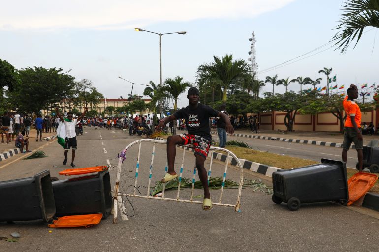 A demonstrator sits on a barricade blocking a road near the Lagos State House,