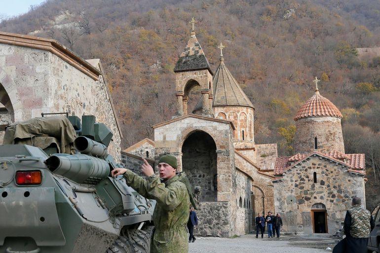 A service member of the Russian peacekeeping troops stands next to a military vehicle at Dadivank monastery in Kalbajar district