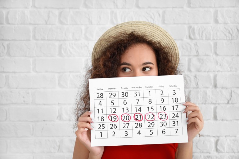 woman holding calendar with marked days of menstruation on white background; Shutterstock ID 1387291721; Department: -