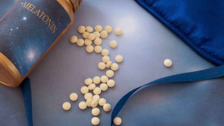 Melatonin supplements and sleep mask on the blue background