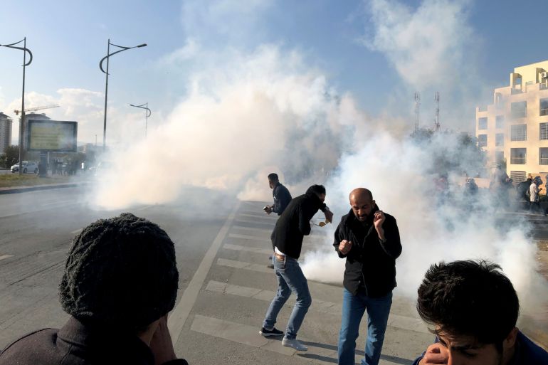 Kurdish demonstrators react to tear gas during a protest over unpaid salaries of the public servants by the Iraqi Kurdish regional government, in Sulaimaniyah