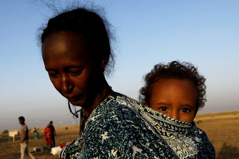An Ethiopian woman who fled the ongoing fighting in Tigray region, carries her child near the Setit river on the Sudan-Ethiopia border in Hamdayet village in eastern Kassala state, Sudan November 22, 2020. REUTERS/Mohamed Nureldin Abdallah/File Photo TPX IMAGES OF THE DAY SEARCH "GLOBAL POY" FOR THIS STORY. SEARCH "REUTERS POY" FOR ALL BEST OF 2020 PACKAGES.