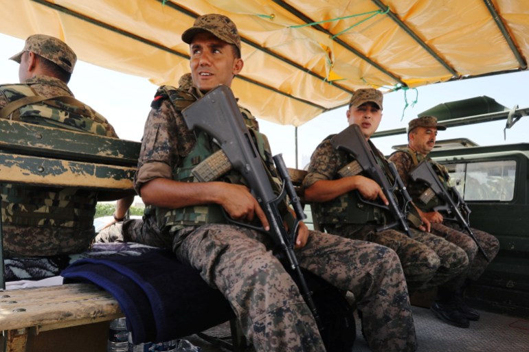 Army soldiers sit on a truck outside a sports hall where ballot boxes and election material are collected to be distributed to polling stations in Tunis