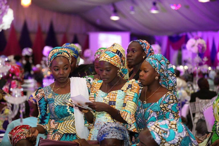 Some of the 106 girls who were kidnapped by Boko Haram militants in the Nigerian town of Chibok look through a set of photographs during the the send-forth dinner organised for them in Abuja