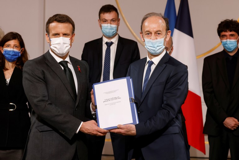 French President Emmanuel Macron holds a document with historian Vincent Duclert, who heads the Rwandan commission, at the Elysee Palace in Paris