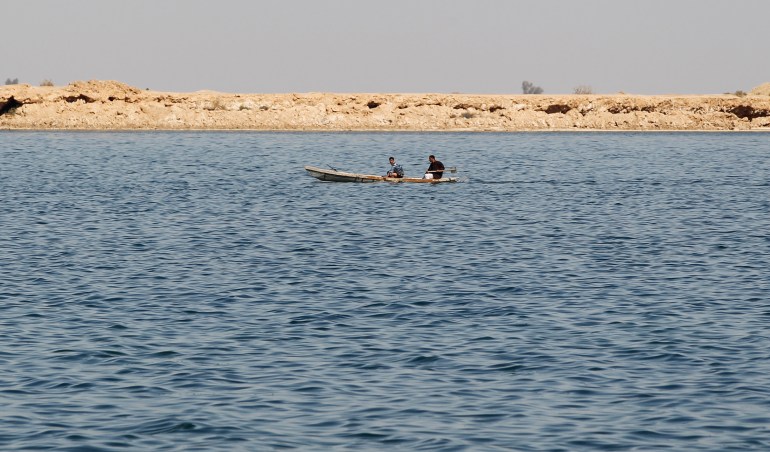 Two men in a boat travel on Sawa lake in Samawa
