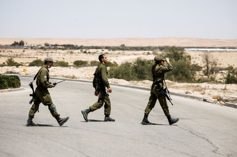 Israeli soldiers survey the area after a Syrian missile exploded in southern Israel, the Israeli military said, in Ashalim