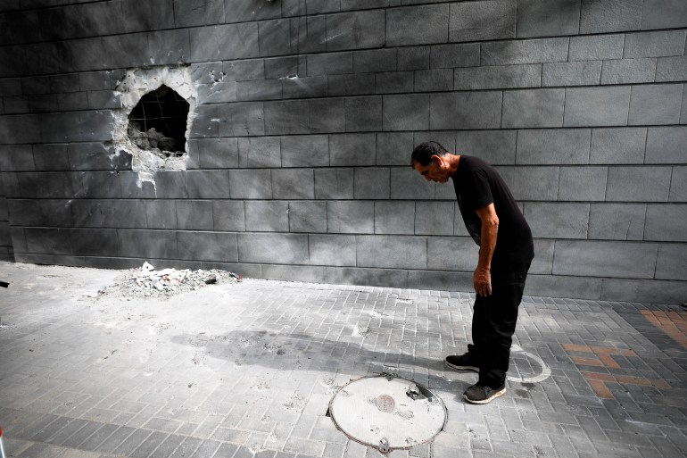 An Israeli man looks on at a residential building after a rocket launched overnight from the Gaza Strip hit the building in Ashkelon