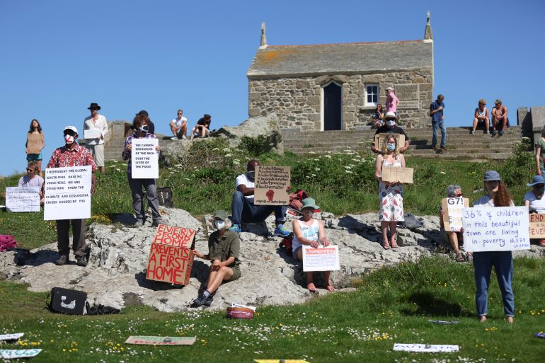 نشطاء يحملون لافتات تطالب بالعدالة العرقية وإنقاذ البيئة خلال تظاهرة في جزيرة سانت آيفز، خلال قمة مجموعة السبع في كورنوال (رويترز)