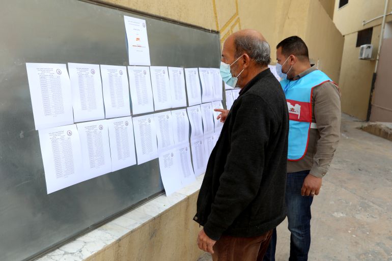 A man searches for his name on a list at a polling station during the municipal elections in Tripoli