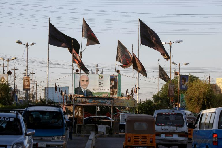 Religious flags are pictured near an election campaign poster ahead of the parliamentary election, in Baghdad