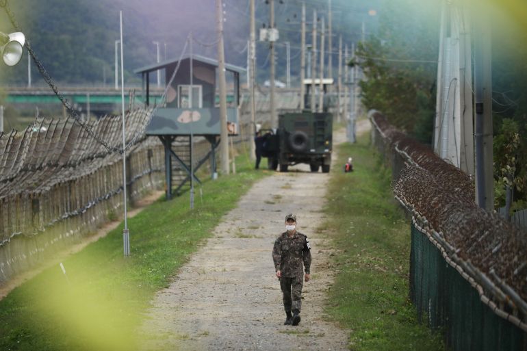 A South Korean soldier walks along a military fence near the demilitarized zone separating the two Koreas in Paju