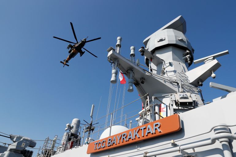 A military attack helicopter flies over the TCG Bayraktar (L-402) taking part in a landing drill during the Blue Homeland naval exercise off the Aegean coastal town of Foca in Izmir Bay