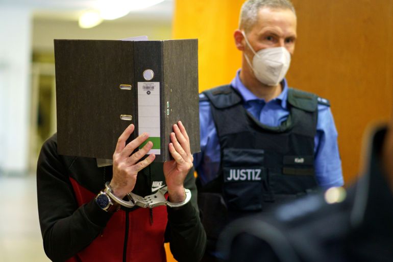 Iraqi defendant covers his face as he arrives for his verdict in a courtroom in Frankfurt